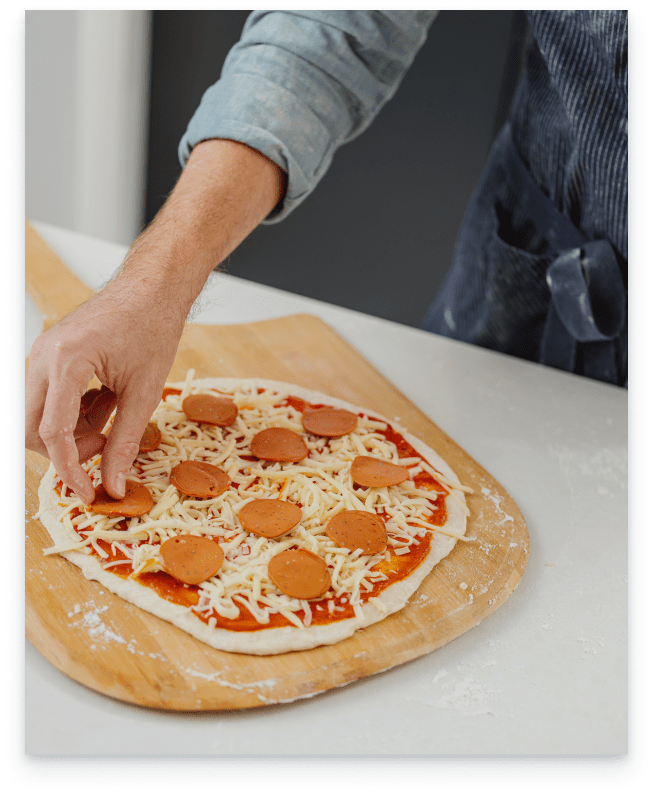 Greg adds cheese and pepperoni to his pizza.